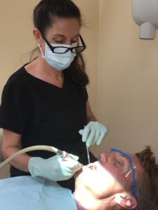 One of the hygenists at Steven M. Miller DDS pracice, working on a patient and providing essential dental services to patients in Wellington FL.